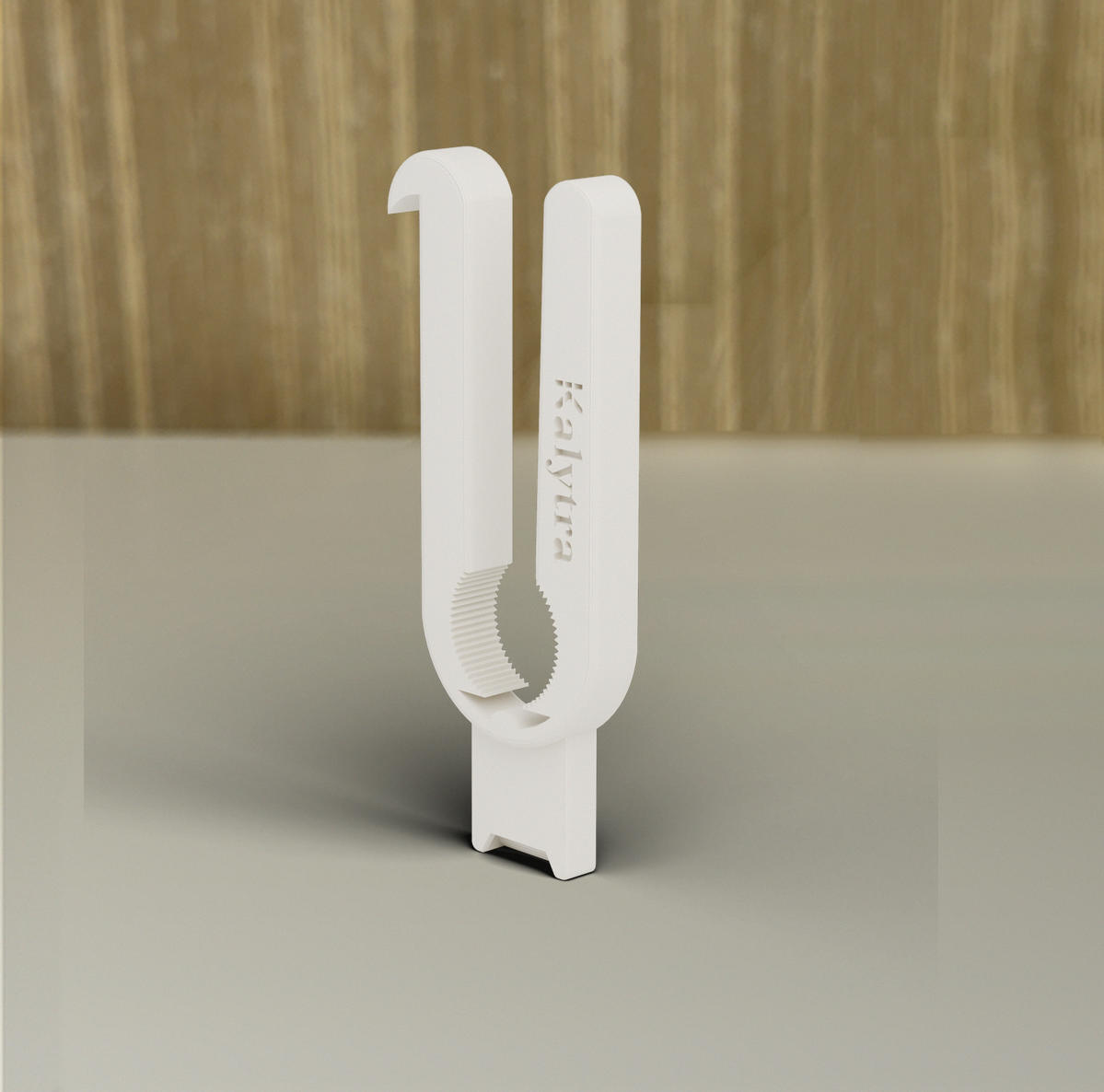 Ouvre-bouteille Kalytra imprimé en 3D, posé sur une table blanche devant un mur de bambou